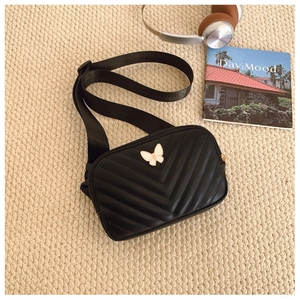 Detail of black V-quilted kids crossbody bag with white butterfly metal buckle and strap
