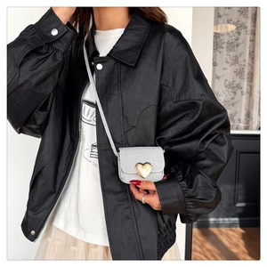 Détail du mini sac argenté pailleté avec fermoir cœur doré sur veste en cuir chic