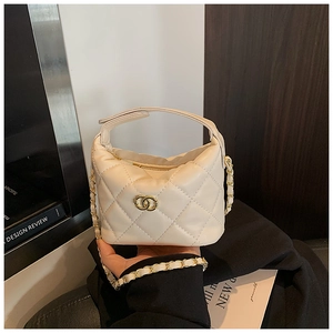 Détail d'un sac matelassé beige avec fermoir en métal doré et bandoulière en chaîne
