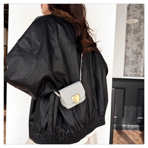 Détail d'un mini sac bandoulière crème avec texture tissée et fermoir cœur doré