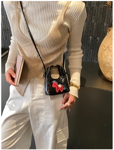 Dettaglio mini borsa nera trapuntata con ricamo a forma di cavallo rosso e tracolla