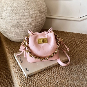 Détail du sac seau matelassé rose avec chaîne dorée et fermeture à cordon