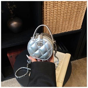 Detail der silbernen gesteppten Mini-Rundtasche mit Metalllogo und Kettengurt in der Hand