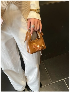 Detail of a brown quilted leather mini handbag with a small horse embroidery on the front