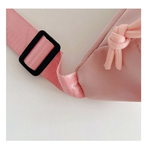 Détail du sac bandoulière rose pour enfant avec boucle noire et texture en nylon