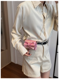 Detailed shot of a mini pink metallic bow crossbody bag with a gold chain strap