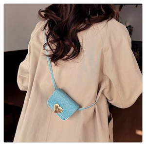 Détail d'un mini sac bleu clair à paillettes avec un fermoir doré en forme de cœur