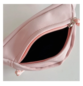 Détail du sac de poitrine en toile rose avec fermeture éclair et doublure noire