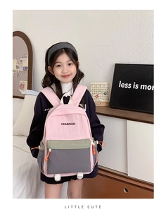 Girl wearing a pink and olive color-block school backpack with adjustable straps