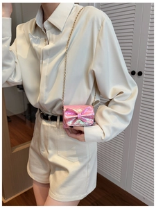 Detail of pink metallic crossbody bag with large bow and golden chain strap for girls