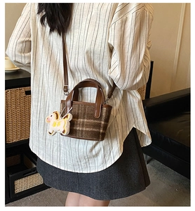 Detail view of brown plaid mini bucket bag with leather strap and white horse charm