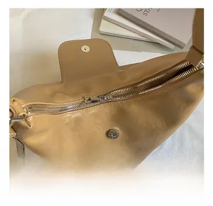 Detailed close-up of the smooth metal zipper and silver magnetic buckle on a khaki tote bag