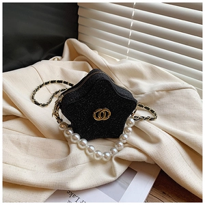 Detail of black star-shaped mini bag with pearl handle and gold chain strap