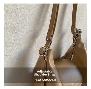 Detail view of the adjustable shoulder strap and silver metal buckle on a light brown bag