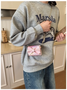 Detailed view of pink iridescent bow crossbody bag with quilted pattern and gold chain