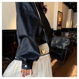 Sac bandoulière pailleté champagne doré avec boucle cœur porté avec une tenue élégante