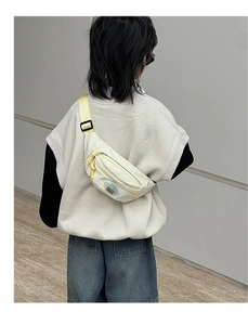 Détail du sac de poitrine enfant en toile crème avec patch dessin animé et sangle jaune