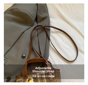 Detail showing the adjustable leather strap and plaid texture of this small crossbody bag