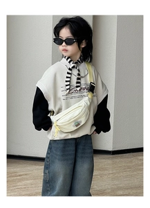 Détail du sac de poitrine enfant en toile crème avec sangle jaune et patch dinosaure