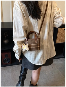 Detail of brown plaid tweed mini bag with leather handles and a cute horse charm