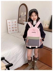Front view of a young girl wearing a pink and green color-block school backpack with straps