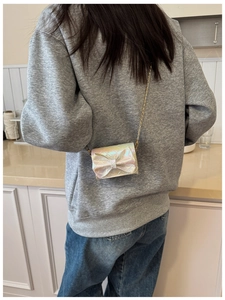 Girl's iridescent mini crossbody bag with bow and gold chain strap shown on model