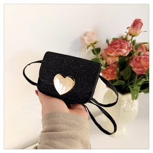 Détail d'un mini sac noir pailleté avec un grand fermoir en métal doré en forme de cœur