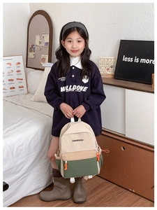 Kids backpack side view with tri-color canvas and orange zipper pulls on polo shirt model