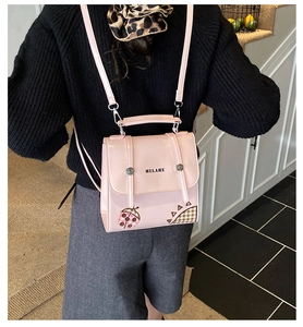 Detailed view of pink glossy PU leather backpack featuring HELAHE lettering and cartoon patches