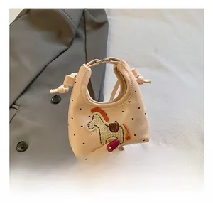 Dettaglio della mini borsa rosa con toppa a forma di pony e fori a cuore rifiniti