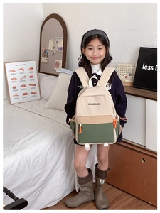 Detail of color-block canvas kids backpack with green and beige panels held by a girl