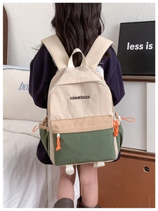 Detail of color-block backpack for kids featuring side drawstring pocket and orange zipper