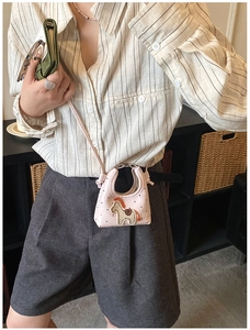 Dettaglio della mini borsa a tracolla rosa con cuore indossata da una modella