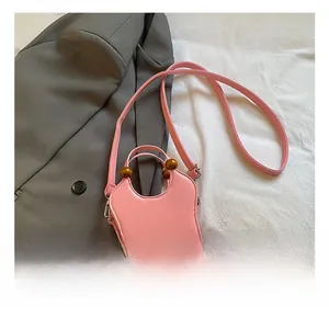 Pink PU leather handbag featuring a dark brown wooden bead handle and crossbody strap