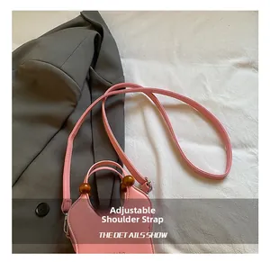 Pink bucket bag with wooden beads and adjustable strap shown on a gray blazer