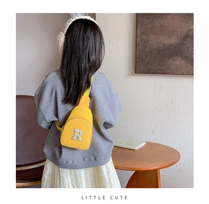 Détail d'un sac bandoulière jaune pour enfant avec patch lettre R blanc en nylon