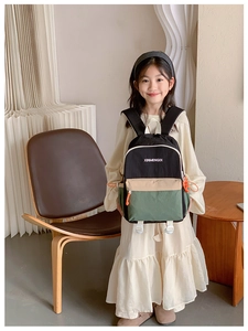 Detailed close-up of colorful school backpack featuring green accents and front zipper pockets