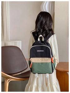 Detail of multi-color backpack with black green and beige panels and white logo