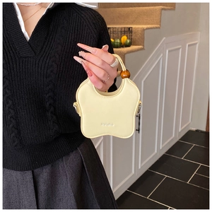 Detail of a creamy yellow wavy mini handbag with a brown wooden bead handle