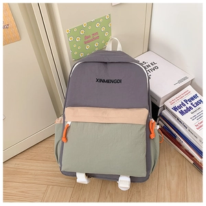 Detail of color-block school backpack showing gray nylon fabric and brand embroidery