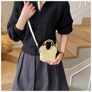 Detail of butterfly-shaped cream bucket bag with vintage wooden bead handle and logo