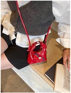 Dettaglio mini borsa rossa a tracolla con motivo a cuore e ricamo sulla cinghia
