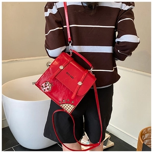 Detail of red square crossbody bag with ladybug embroidery and checkered stitching
