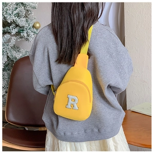 Détail d'un sac bandoulière jaune pour enfant avec écusson lettre R en peluche