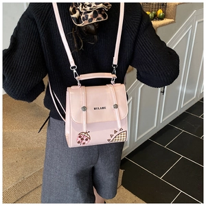 Rear view of a pink ladybug print backpack with adjustable straps on a child model