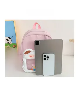 Pink kids backpack with a cute white cow pouch and clear window detail shown with tablet
