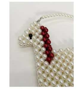 Close-up of handmade white pearl beaded bag with a unique red beaded horse pattern