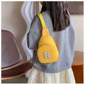Gros plan d'un sac bandoulière jaune pour enfant avec patch lettre R en peluche douce