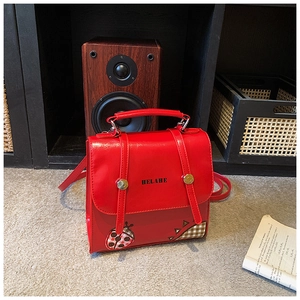 Detail of red PU leather backpack with ladybug patch and gold circular buckle