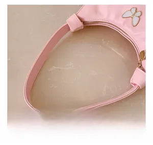 Détail d'un sac à main rose pour enfant avec ornement papillon blanc en métal